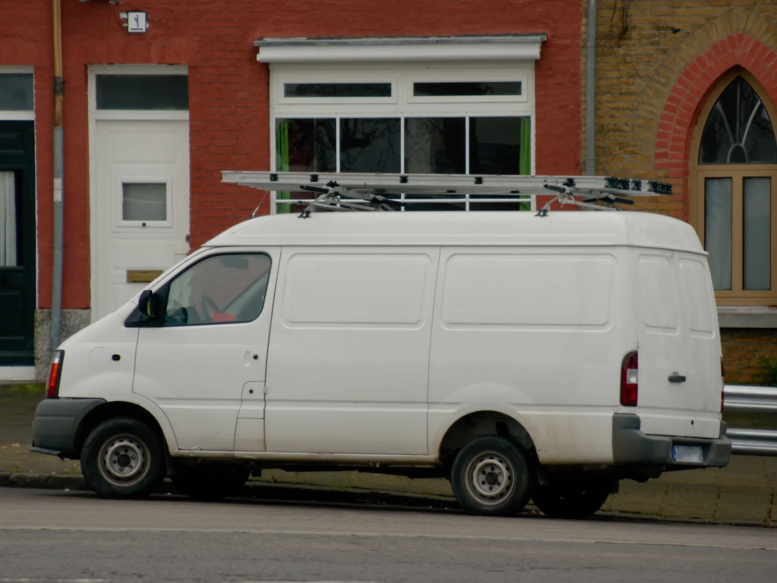 Witte bestelwagen geparkeerd in een woonstraat met rijwoningen